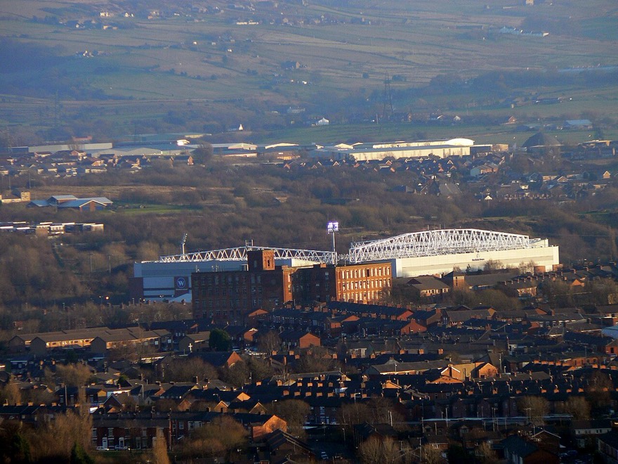 Ewood Park visto das colinas, erguendo-se entre os telhados e as chaminés das antigas tecelagens de Blackburn.