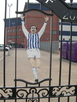 Portrait of West Bromwich Albion footballer Jeff Astle on the Astle Gates, The Hawthorns, West Bromwich. Portrait captures Astle celebrating his winning goal in